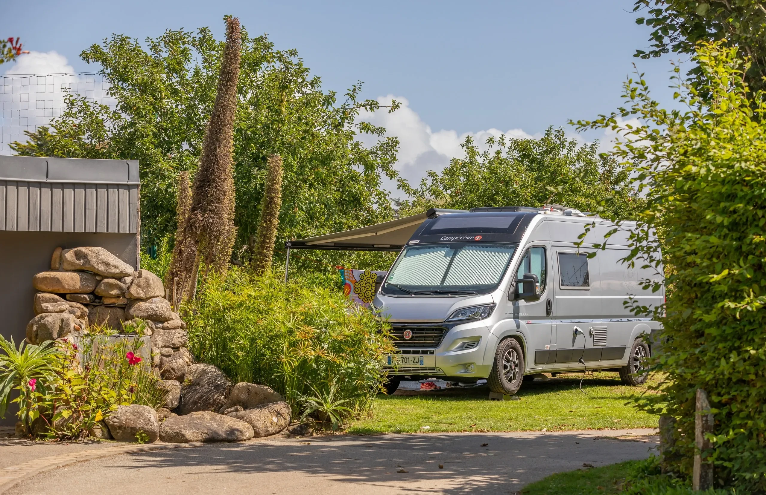 Camping-car stationné dans un jardin verdoyant - Camping Bretagne Parc Aquatique - Camping Les Embruns